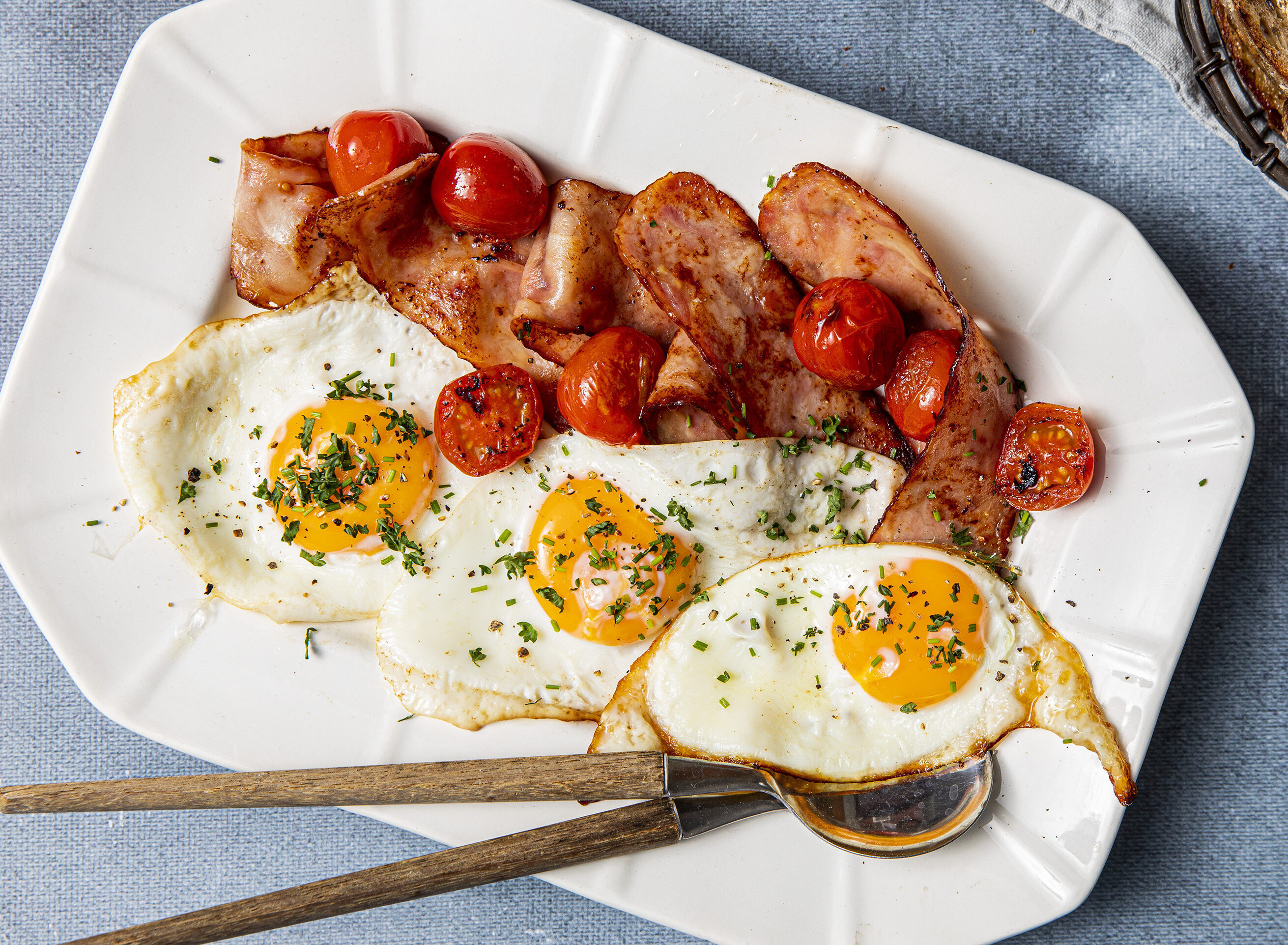 Egg og bacon anrettet på hvitt fat med cherrytomater