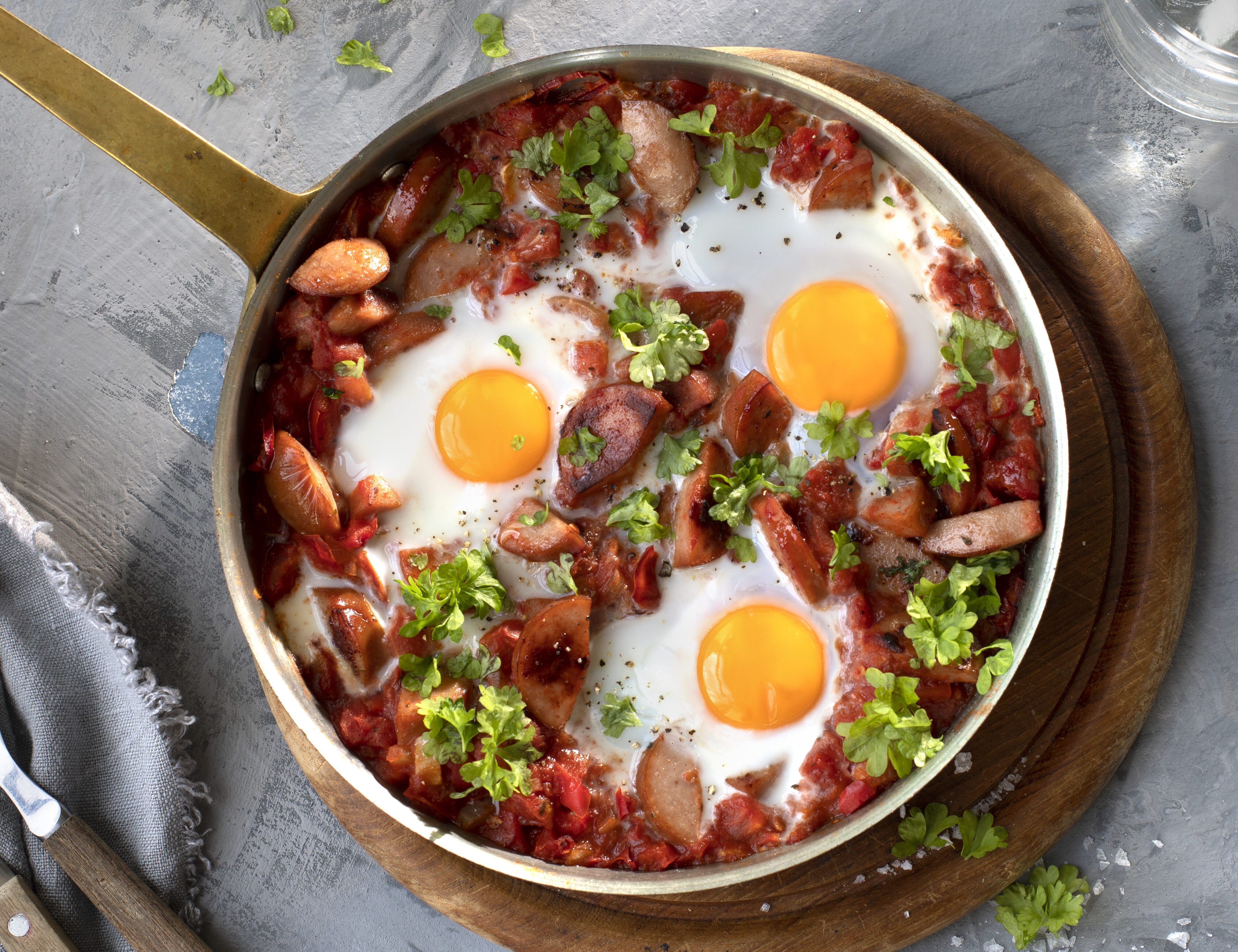 Shakshuka med pølse, egg og hakkede tomater i panne