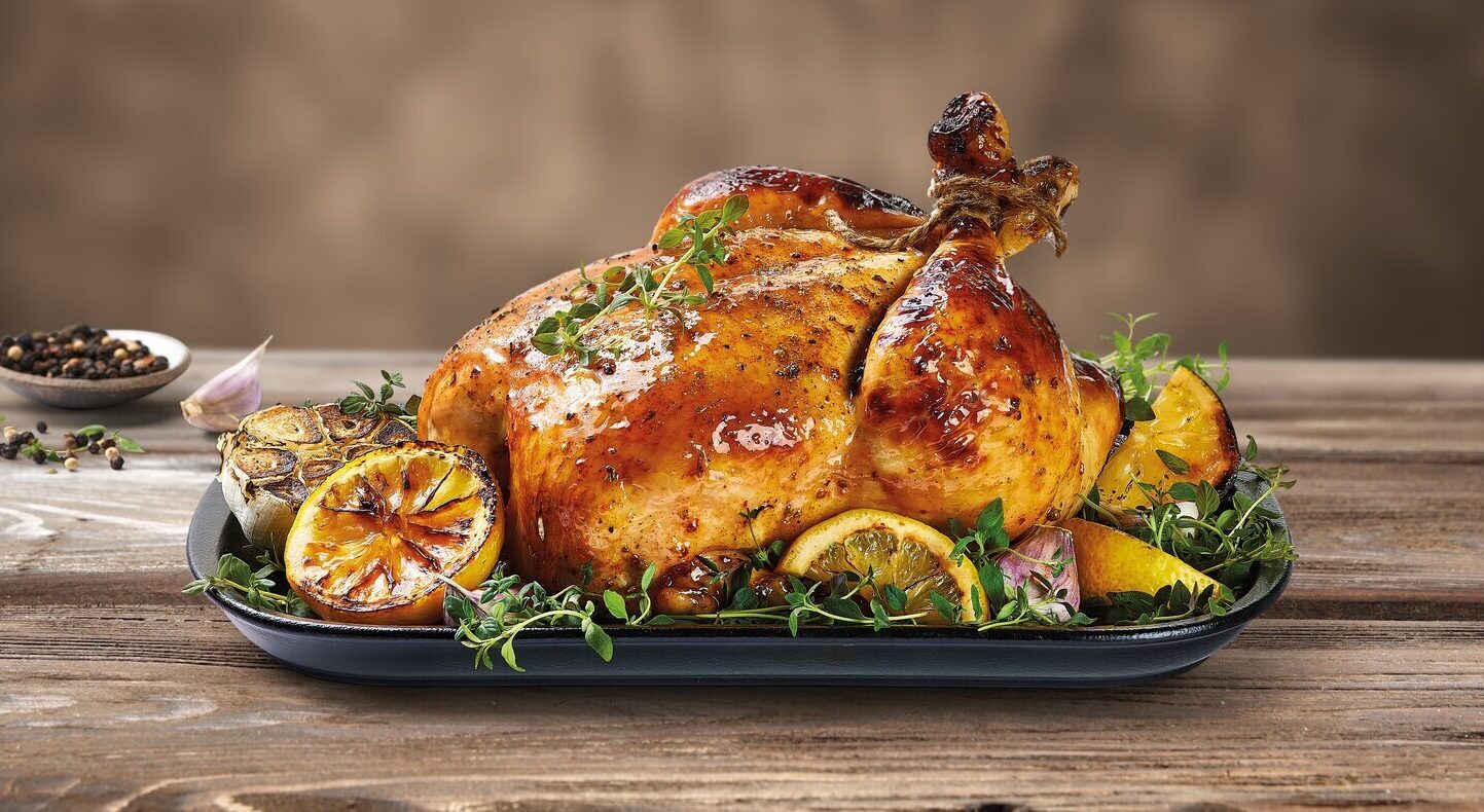 Ferdigstekt hel kylling dandert på et fat med urter og sitron