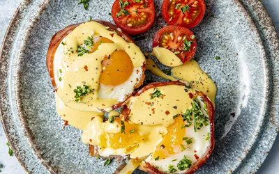 Egg og bacon frokostpaier anrettet med tomater og hollandaise saus